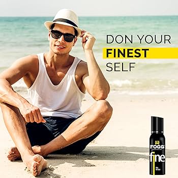 Man sitting on the beach with sunglasses and a hat, next to a Fogg deodorant can.