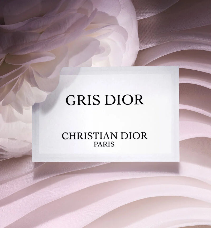 Elegant white label card for Gris Dior perfume displaying Christian Dior Paris branding against soft fabric texture, emphasizing the luxury Dior perfume's prestigious identity.