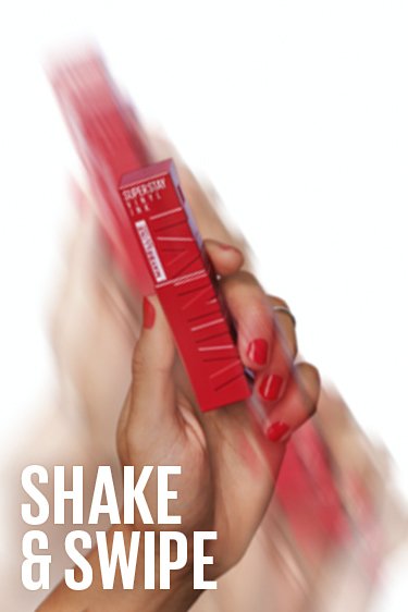 A hand shaking a tube of Maybelline Superstay Vinyl Ink lipstick, demonstrating the 'shake and swipe' application method - Khayest