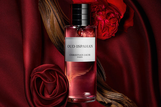 "Premium Oud Ispahan Dior Perfume bottle with pink-hued fragrance displayed against luxurious red fabric and rose petals, highlighting the elegant packaging"